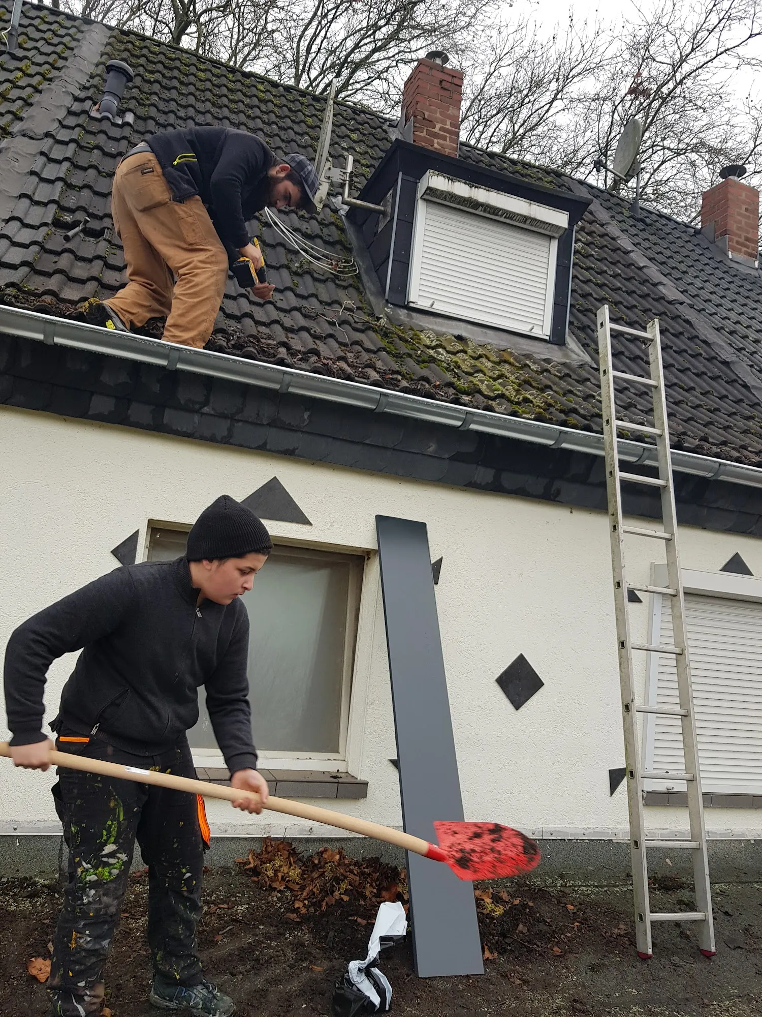 Zwei Dachdecker bei der Arbeit an einem Wohnhausdach