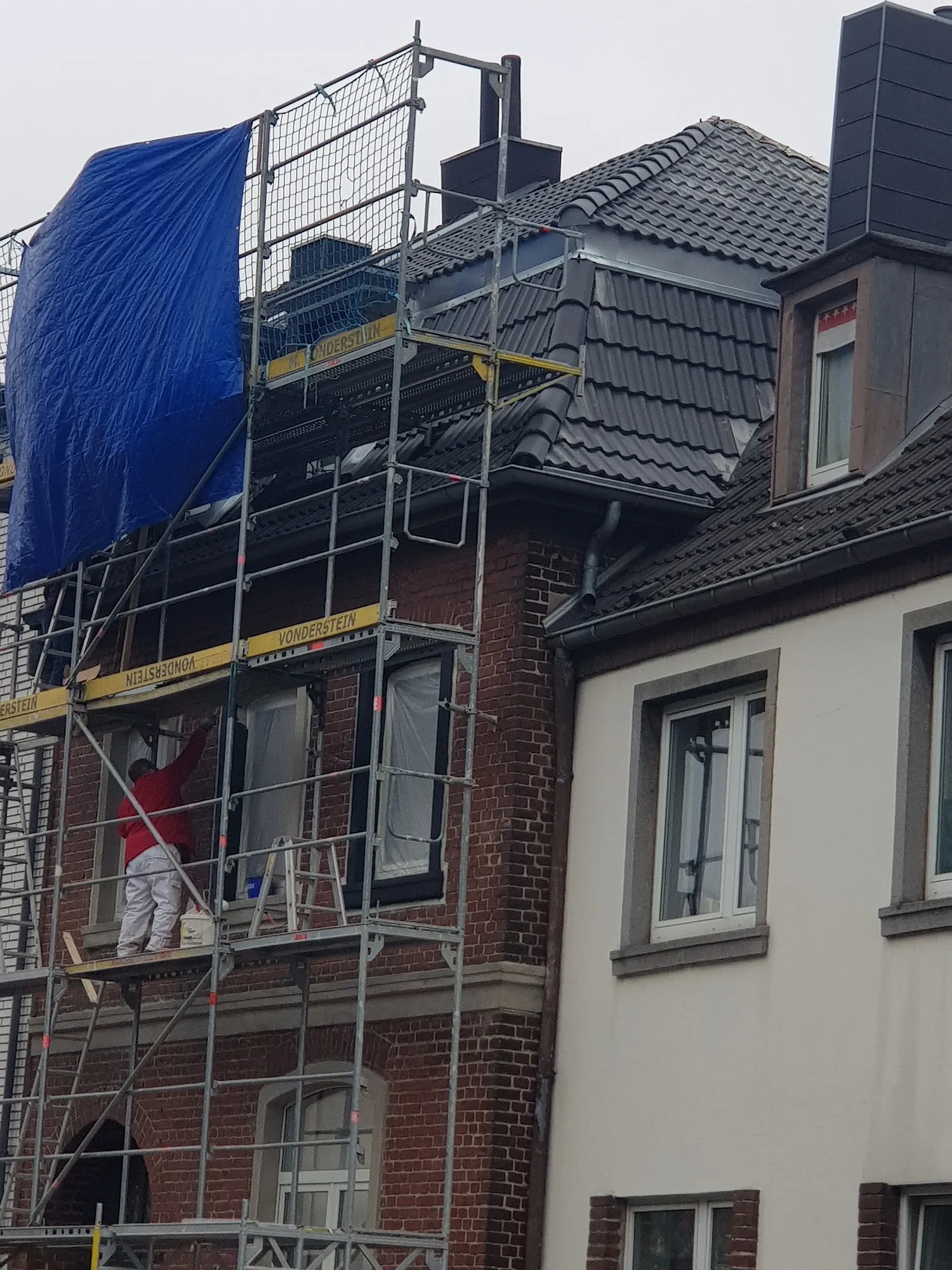 Aufgebautes Gerüst vor einem Backsteingebäude für Dacharbeiten