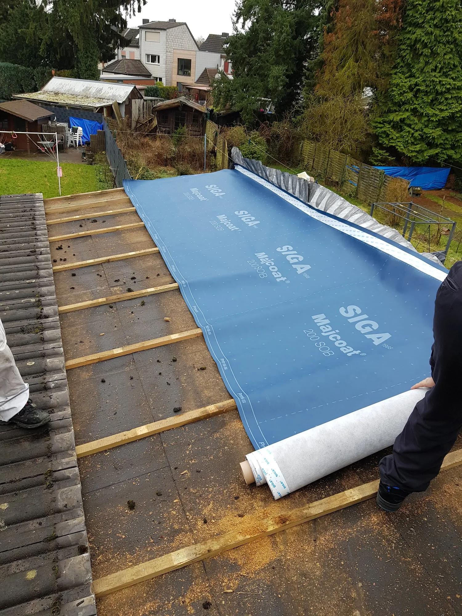 Arbeiter verlegen blaue SIGA Majcoat Unterspannbahn auf einem Dach